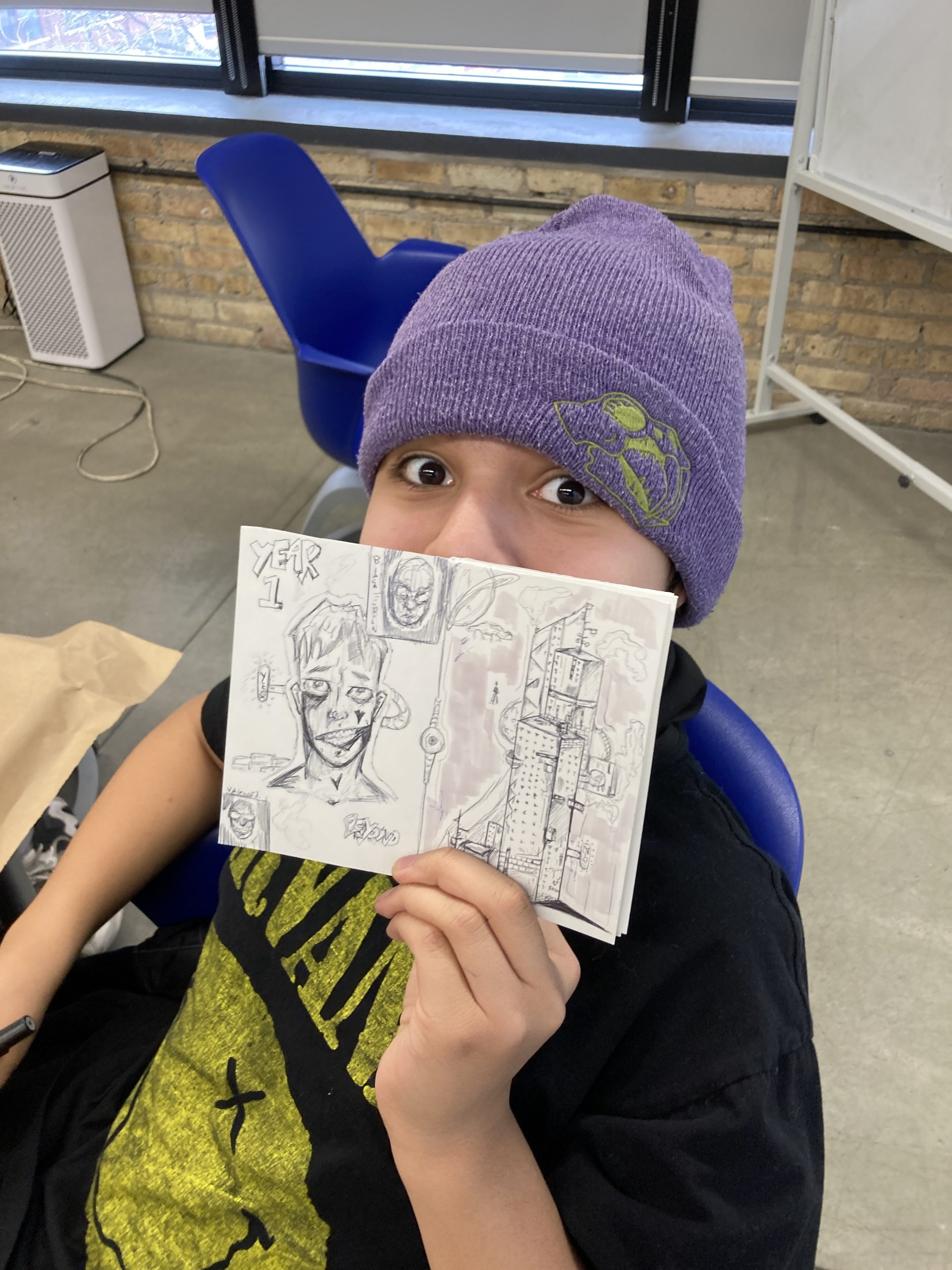 A young artist proudly showing off their zine or comic.