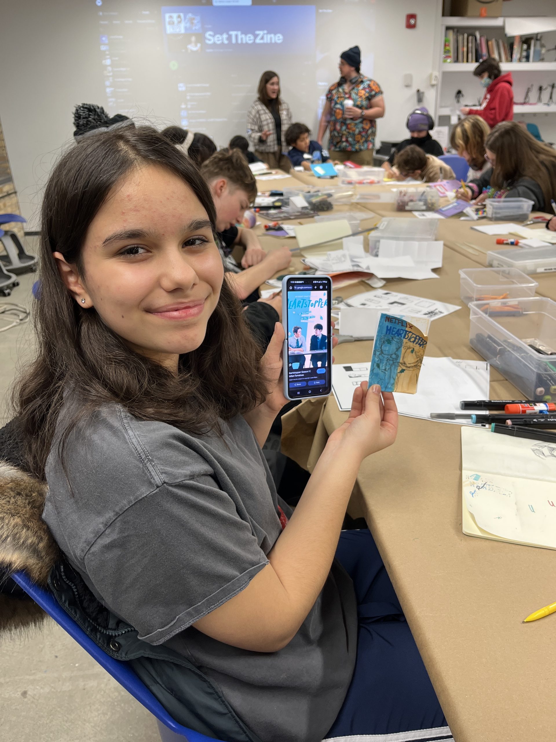 A young artist proudly showing off their zine or comic.