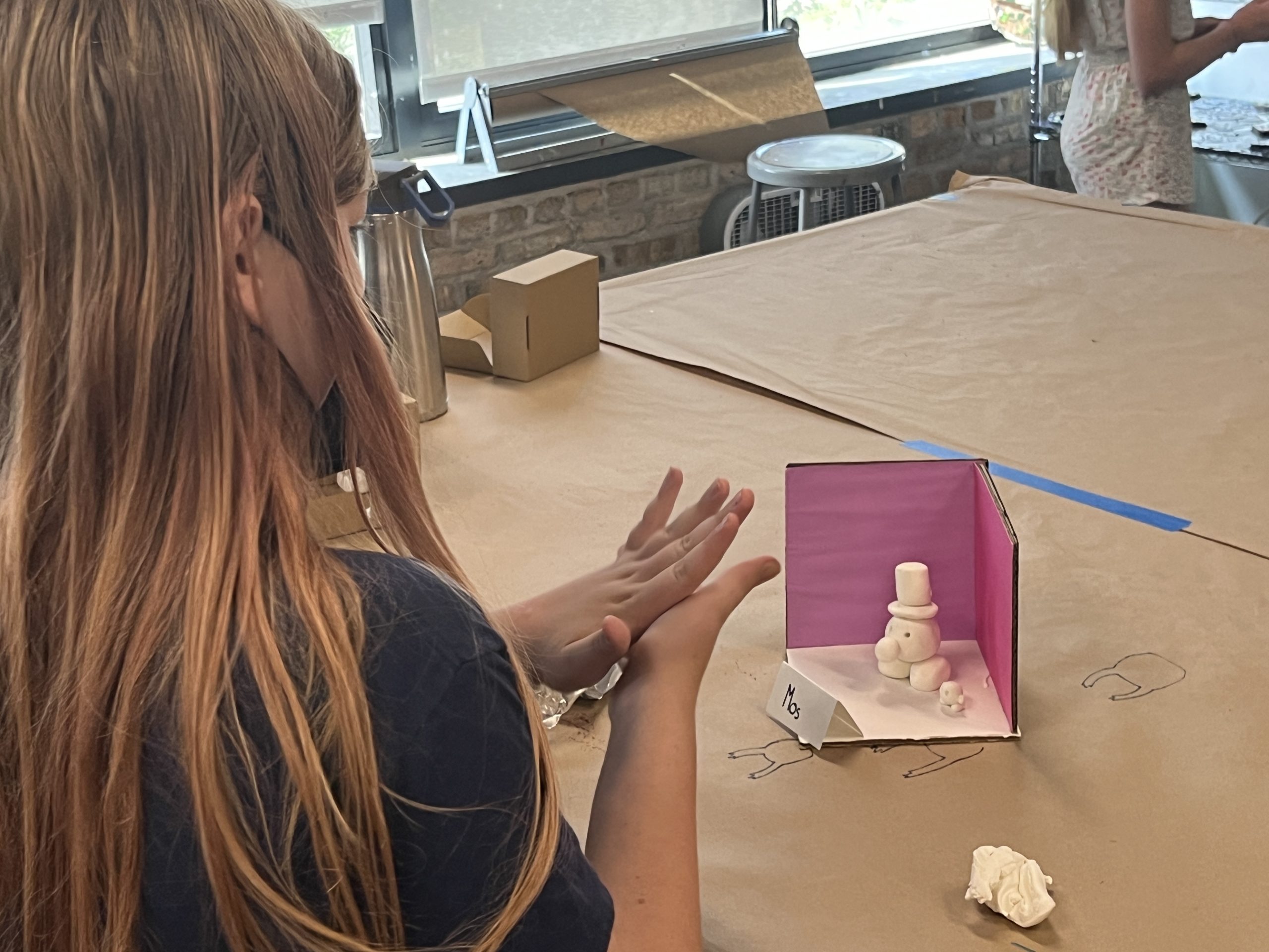 A young artist sculpting their mini world diorama.