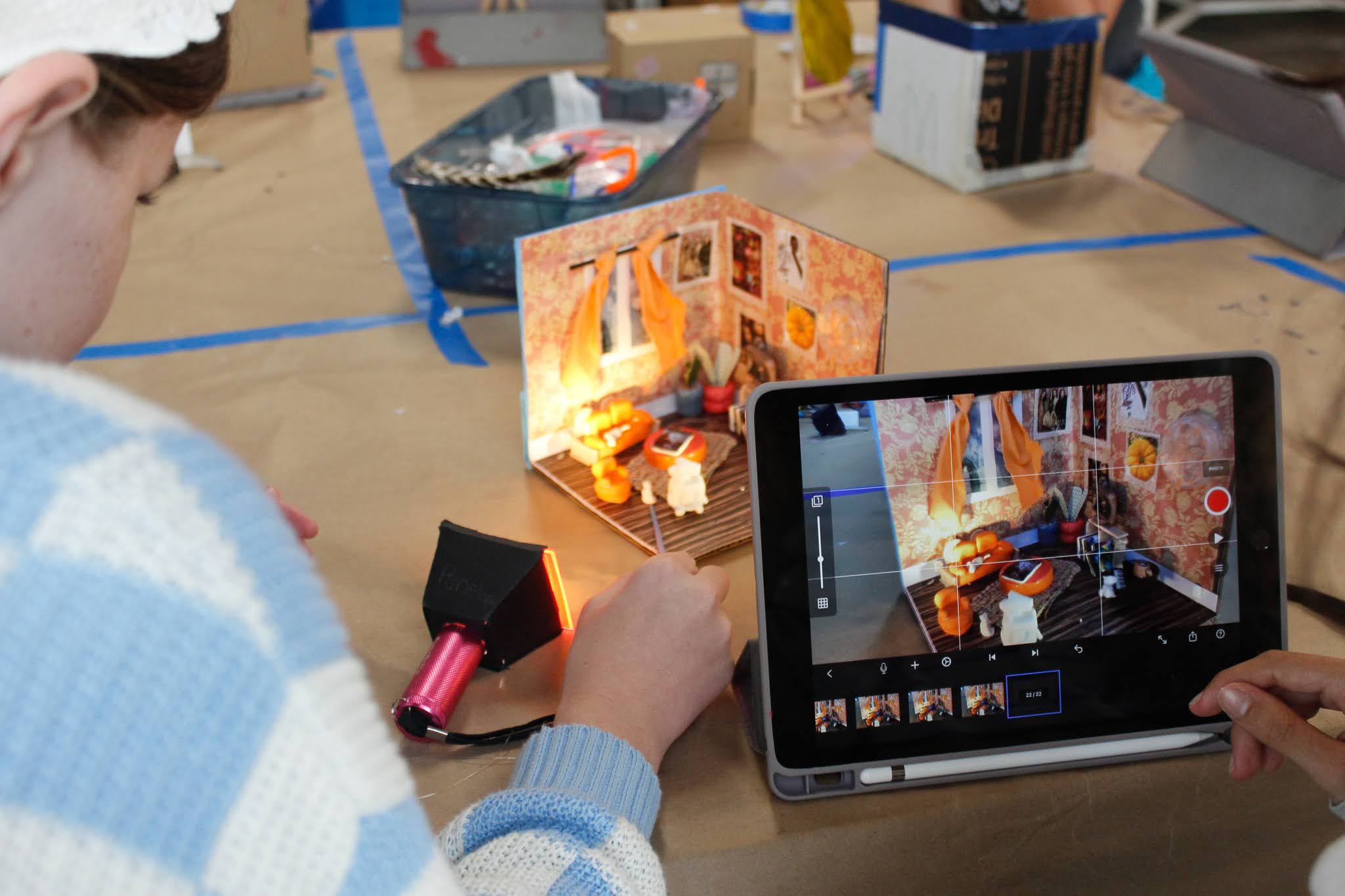 A young artist photographing their sculpted mini world.