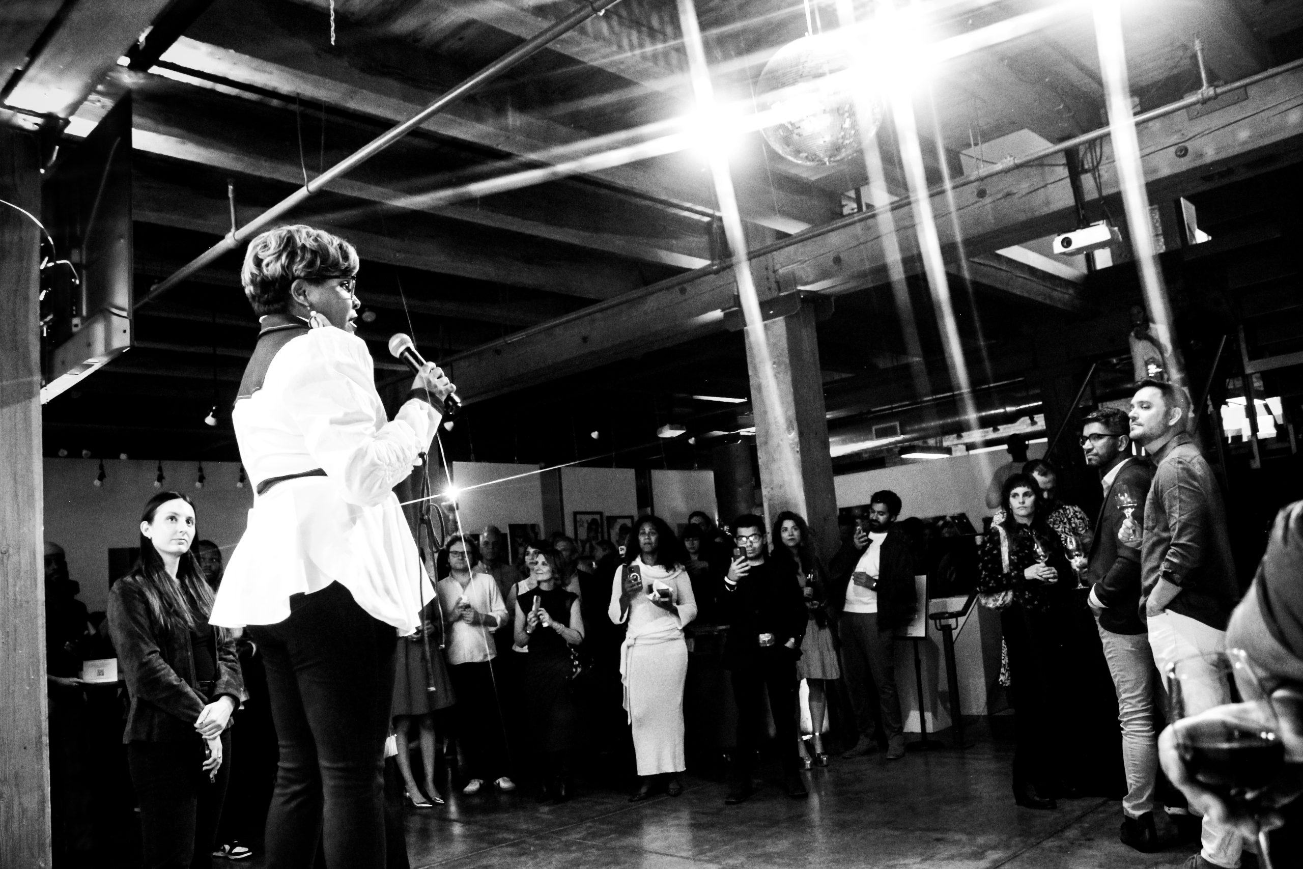 Executive Director Akilah Halley standing on a podium holding a mic speaking to crowd at Art Fair 2025