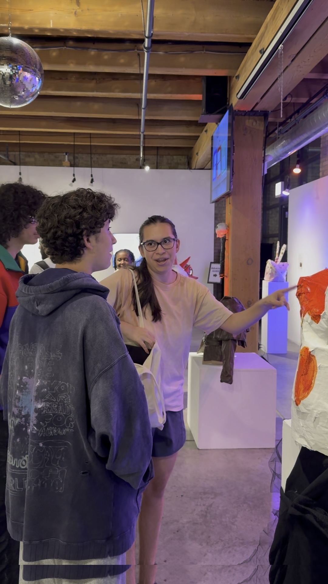 A young artist excitedly points out their artwork at the Marwen Summer 2025 Exhibition Celebration.